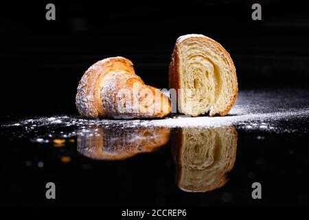 Croissants with filling. Homemade pastries, croissants cut in half and sprinkled with icing. Stock Photo