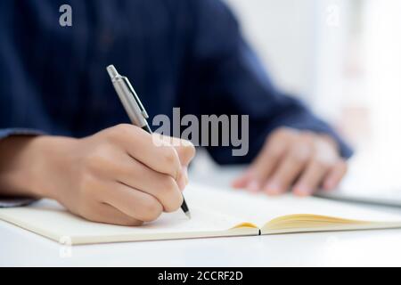 Closeup hand of man writing on notebook with pen on desk, freelance is author, businessman write on notepad on table, book, letter and report, finance Stock Photo