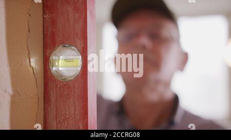 Senior man using the leveler tool on the wall. home improvement concept. Selective soft focus. High quality photo Stock Photo