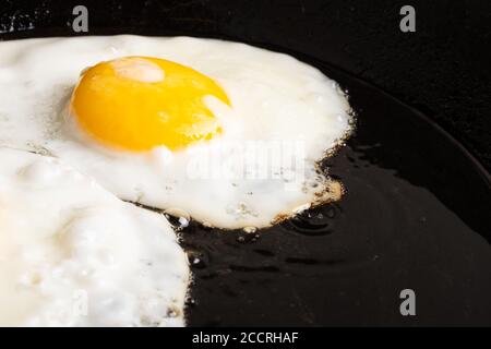 fried chicken egg in a black cast iron pan close-up, breakfast. Stock Photo