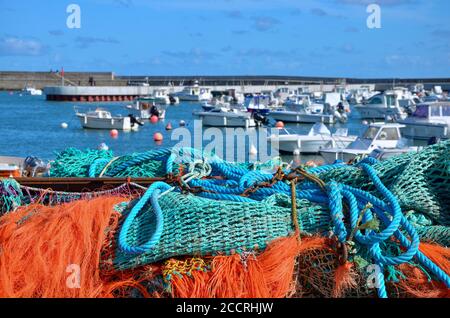 he harbor of the community of Port-en-Bessin-Huppain in Normandy, France, coast of English Channel, colorful fishing nets in front, blurred boats