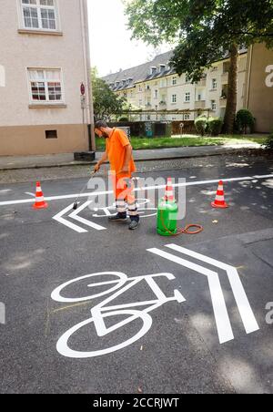 Essen, Ruhr Area, Nordrhein-Westfalen, Germany - new bike street, a lane marker while applying the bicycle pictograms, here in Busehofstrasse in the d Stock Photo