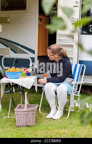 Woman sitting in front of a camping car with chanterelles. Stock Photo