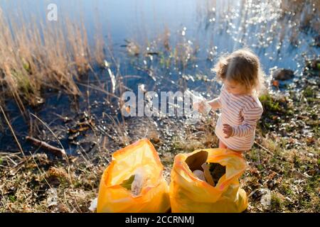 Top view of small child collecting rubbish outdoors in nature, plogging concept. Stock Photo