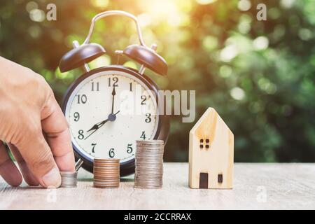 Close-up of male hand holding house model with green bokeh background saving money to prepare for the future. Stock Photo