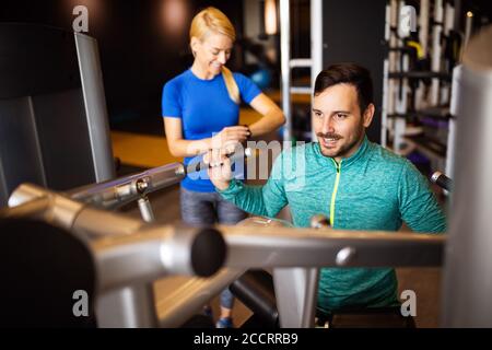 Fit happy man exercising at the gym on a machine Stock Photo