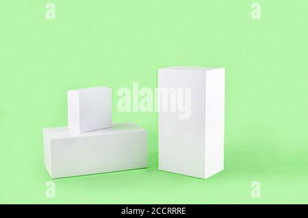 Three white geometric figure, a rectangular with shadows on a light green background. Stock Photo