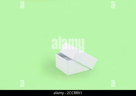 Open white gift box with shadows on a light green background. Stock Photo