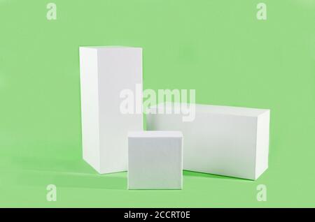 Three white geometric figure, a rectangular with shadows on a light green background. Stock Photo