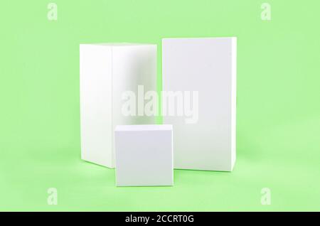 Three white geometric figure, a rectangular with shadows on a light green background. Stock Photo