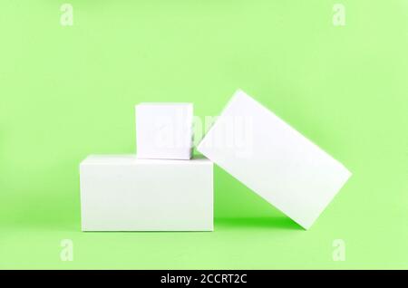 Three white geometric figure, a rectangular with shadows on a light green background. Stock Photo