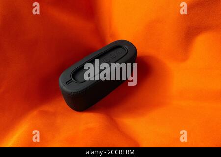 Small black wireless speaker on orange background Stock Photo