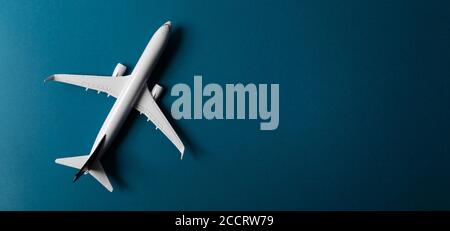 white airplane model on blue paper background with copy space banner. top view