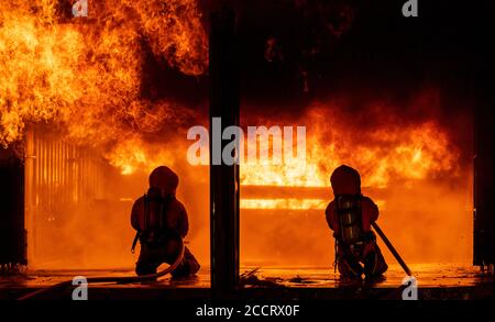 Firefighters using water fog fire extinguisher to fighting with the fire flame in large building. Firefighter and industrial safety disaster and publi Stock Photo