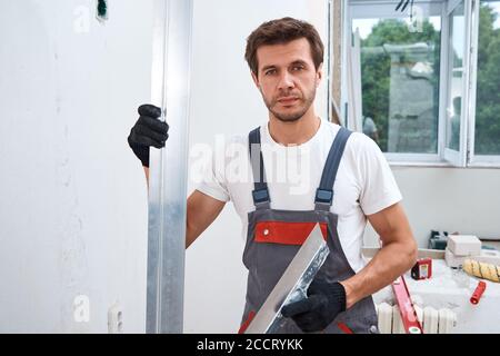 Male worker plastering a wall using a long spatula. Renovation concept Stock Photo