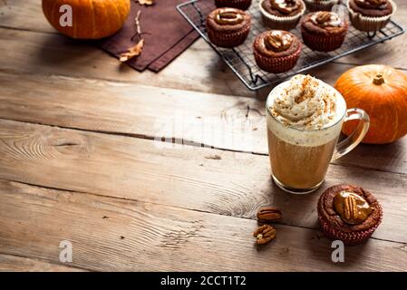 Pumpkin Spice Latte. Seasonal coffee drink and fresh pumpkin muffins for cozy autumn breakfast, copy space. Stock Photo