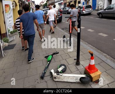 Cracow. Krakow. Poland.Damaged e-scooter tossed on the sidewalk with broken steering column. People passing by. Stock Photo