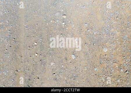Above view of ground, brown soil, arid sandy land with tiny stones as background, texture, material. Empty dry rural road with wheel trace. Stock Photo