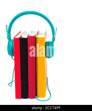 Vertical shot of four colorful books standing on end with a pair of turquoise headphones plugged into them.  Isolated on white.  Copy space. Stock Photo