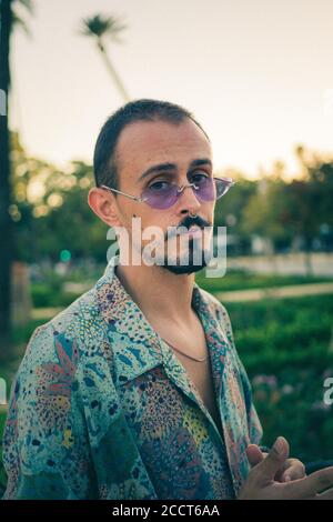 Portrait of a young male with a piercing on his nose wearing purple vintage sunglasses Stock Photo