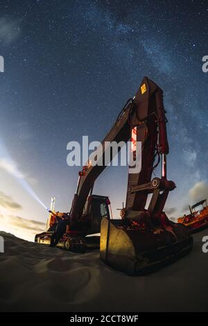 Excavator working under the night sky with the milky way in Valdevaqueros, Cadiz, Andalucia Stock Photo