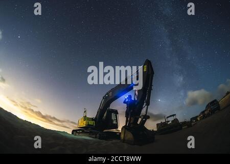 Excavator working under the night sky with the milky way in Valdevaqueros, Cadiz, Andalucia Stock Photo