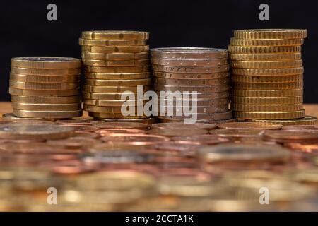 Stacks of euro coins with blurred coins in the foreground and a black background Stock Photo