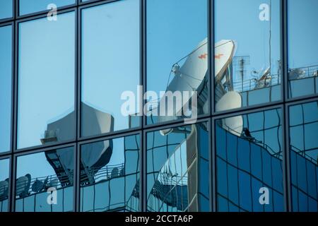 Satellite dishes reflected in the windows of a modern office building Stock Photo