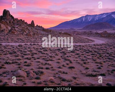 Sunet behind rock formations and a dirt road, desert landscape. Stock Photo