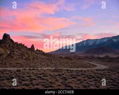 Sunset behind rock formations in an arid desert landscape. Stock Photo