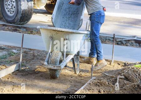 Wheelbarrow with shovel full of cement concrete of concrete mixer truck in industrial worker Stock Photo