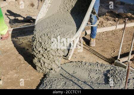 Construction process making of freshly poured cement wheelbarrow with shovel full of cement concrete of concrete mixer truck in industrial worker