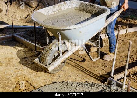 Construction worker pushing wheelbarrow with concrete at building a engineer on construction Stock Photo