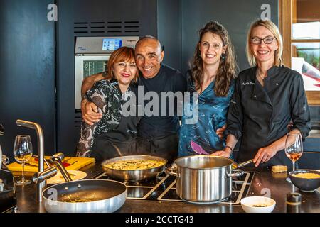 Giulio (2nd from left) and journalist Angela Berg (right) pose with two participants of the wild asparagus cooking workshop in a kitchen near Bagno Vignoni, Val d'Orcia, Tuscany, Italy, surrounded by finished asparagus risotto. Stock Photo