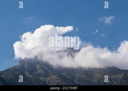 white clouds on top of a mountain on a sunny day Stock Photo