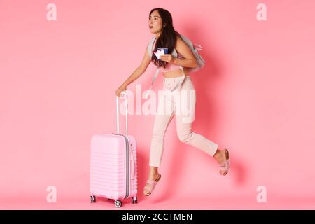 Travelling, holidays and vacation concept. Full-length of worried asian girl tourist being late for flight, running through airport with suitcase Stock Photo