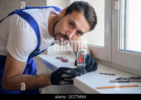 The man measures the distance from the window with a level Stock Photo