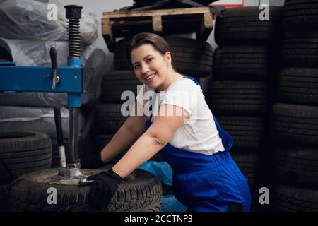 Worker at the workshop is using a press and looking at the camera Stock Photo