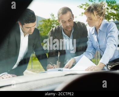 Team Of Business People Signing Contract On Car Hood Stock Photo