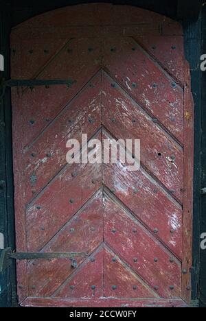 An old red wooden door that is also arched Stock Photo