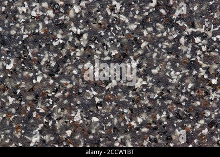 Black plastic with colored speckles throughout. Solid full frame abstract image for background and wallpaper. Close up macro view. Stock Photo