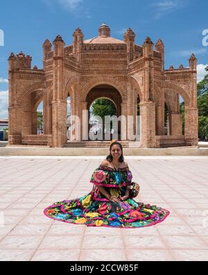 A young woman in the typical dance costume of Chiapa de Corzo poses in front of the La Pila fountain.  Chiapas, Mexico. Stock Photo