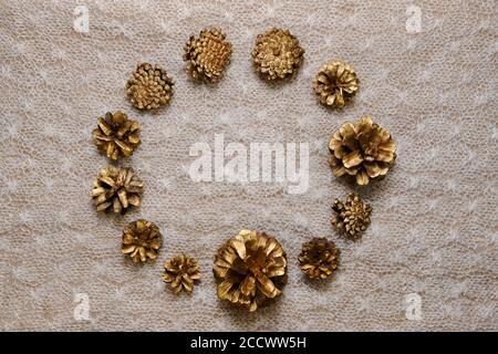A background of gilded pine cones, top view, a round frame in the center, on a knitted canvas in the cold normal light. Stock Photo