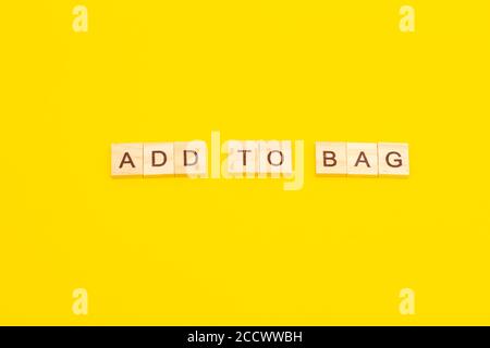 Word ADD TO BAG made from wooden cubes on yellow background Stock Photo