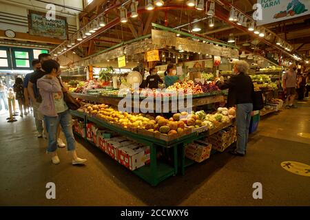 People wearing protective face masks shopping for fruit and vegetables from a produce vendor at the Granville Island Market, Vancouver, BC, Canada Stock Photo