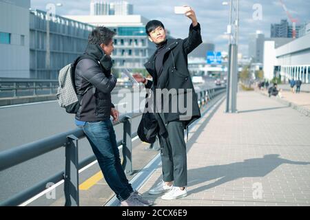 Young asian man taking selfie while travel with friend in the city Stock Photo
