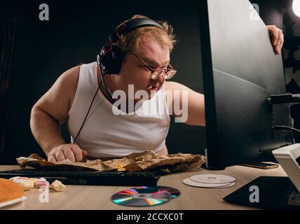 fat man has popping fast food and chewing it while sitting at the table. close up side view photo Stock Photo