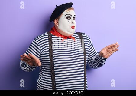 talented actor with raised arms showing pantomime. close up portrait, isolated blue background, studio shot. Stock Photo