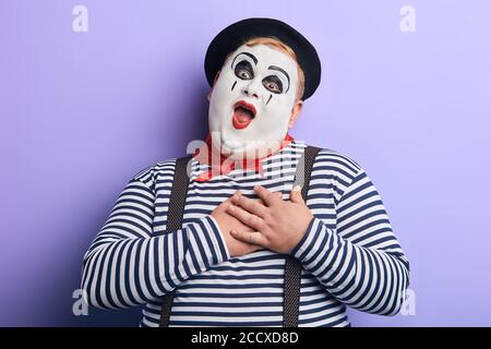 funny man keeps hands on heart expressing love to girlfriend. I love you. tender feeling and emotion . isolated blue background Stock Photo