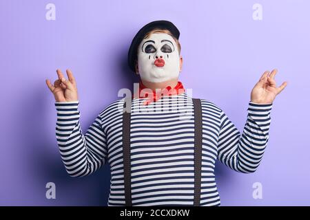 funny plump man with closed eyes, painted face meditating, isolated blue background, studio shot.free time, spare time. lifestyle Stock Photo